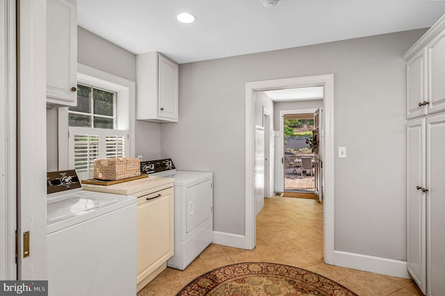 clothes washing area featuring light tile patterned floors, cabinets, a wealth of natural light, and washer and clothes dryer