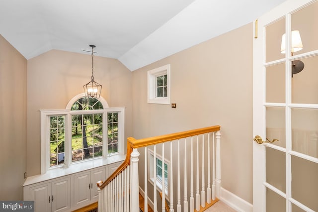 staircase featuring vaulted ceiling, a wealth of natural light, and an inviting chandelier