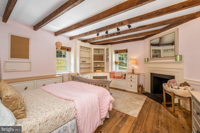 bedroom with beamed ceiling, hardwood / wood-style flooring, and multiple windows