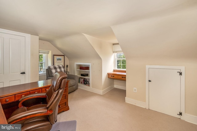 carpeted office with plenty of natural light and vaulted ceiling