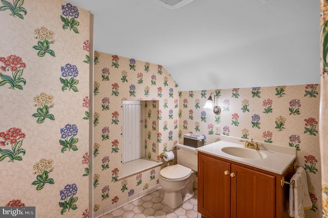 bathroom featuring toilet, vanity, vaulted ceiling, and tile patterned flooring