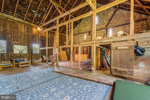 miscellaneous room with high vaulted ceiling and wood-type flooring