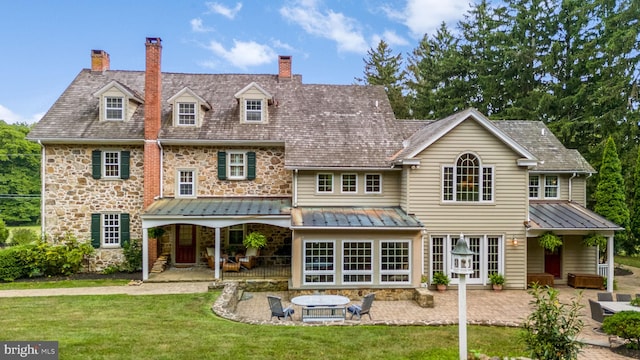 back of property with a yard, a fire pit, and a patio