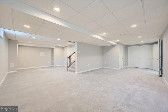 basement with a drop ceiling and light colored carpet