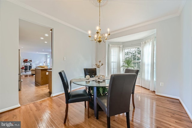 dining room featuring light wood-type flooring, an inviting chandelier, and ornamental molding