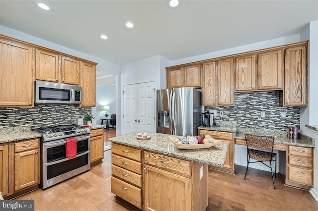 kitchen with a center island, tasteful backsplash, light stone counters, a kitchen bar, and appliances with stainless steel finishes