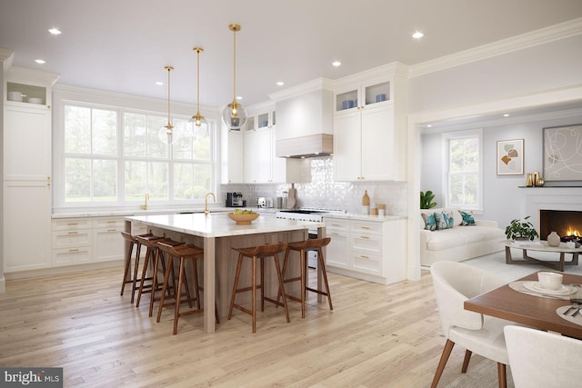 kitchen with pendant lighting, white cabinets, crown molding, light wood-type flooring, and high quality stove