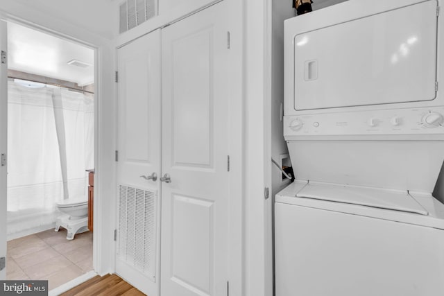 laundry room with light hardwood / wood-style floors and stacked washer / drying machine