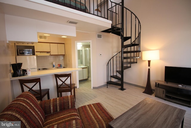 living room featuring sink, a towering ceiling, and light hardwood / wood-style floors