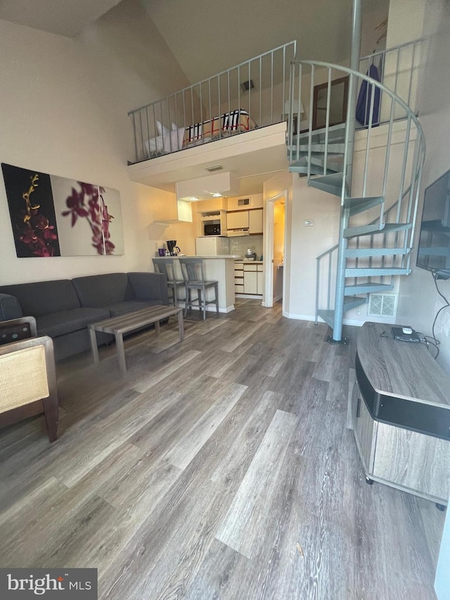 living room with hardwood / wood-style floors and a towering ceiling