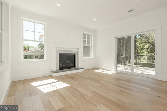 unfurnished living room with light wood-type flooring, a fireplace, and crown molding