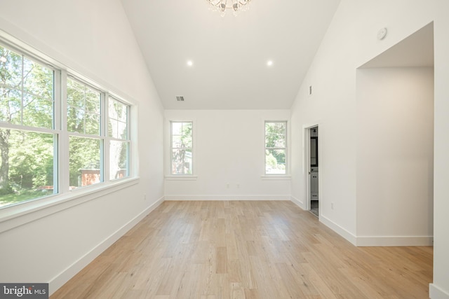 spare room featuring high vaulted ceiling, plenty of natural light, and light hardwood / wood-style flooring