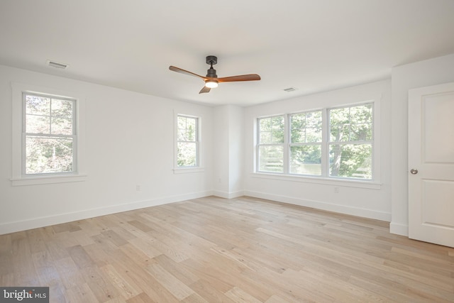 spare room featuring ceiling fan, light wood-type flooring, and a wealth of natural light