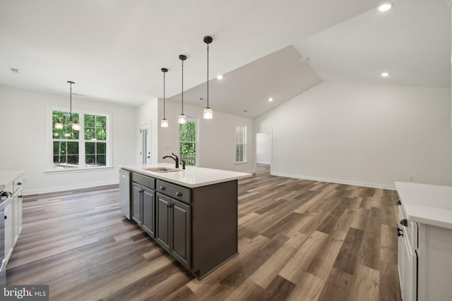 kitchen featuring a center island with sink, sink, hanging light fixtures, dark brown cabinets, and dark hardwood / wood-style flooring