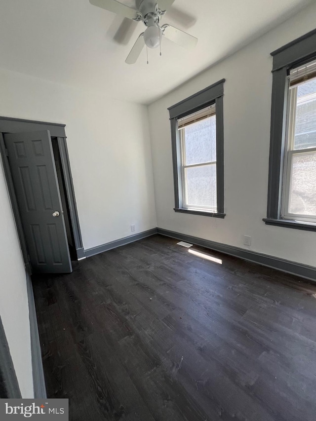 unfurnished room featuring ceiling fan and dark wood-type flooring