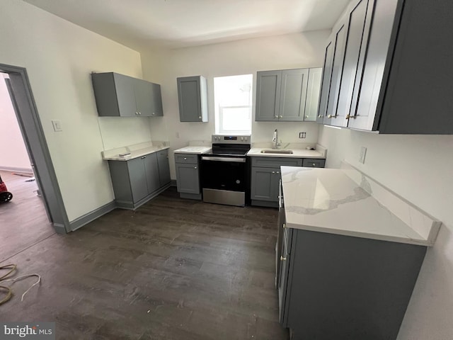 kitchen featuring gray cabinets, dark wood-type flooring, stainless steel electric range, light stone counters, and sink