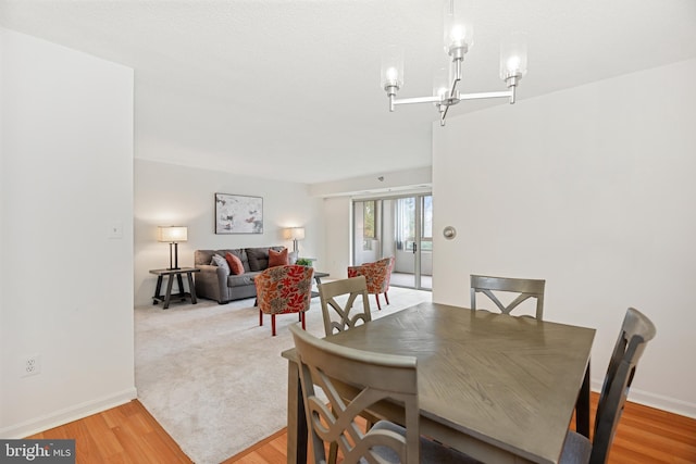 dining room featuring light wood finished floors, baseboards, and a chandelier