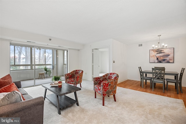 living room with light wood-style flooring, a textured ceiling, visible vents, and a notable chandelier