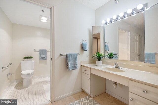 bathroom with baseboards, vanity, toilet, and tile patterned floors