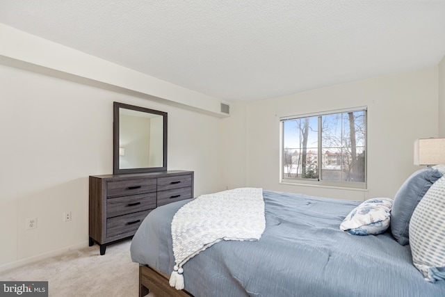 bedroom with light carpet, a textured ceiling, visible vents, and baseboards