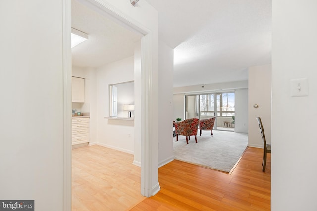 corridor with light wood finished floors and baseboards