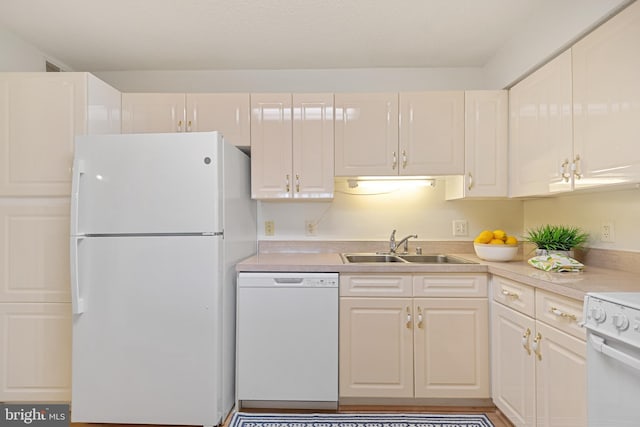 kitchen with white appliances, light countertops, a sink, and white cabinets