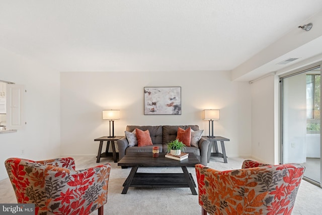 living room with light carpet, visible vents, and baseboards