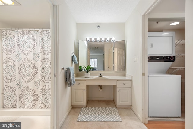 bathroom with a shower with shower curtain, a textured ceiling, stacked washing maching and dryer, and vanity