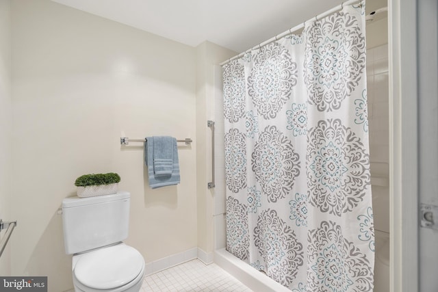 bathroom with toilet, a stall shower, tile patterned flooring, and baseboards