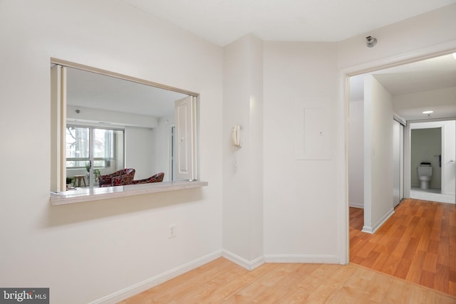 hallway featuring baseboards and wood finished floors