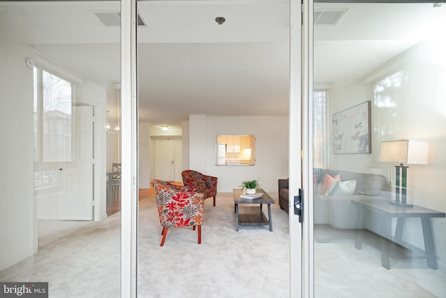 sitting room featuring light carpet, visible vents, and a textured ceiling