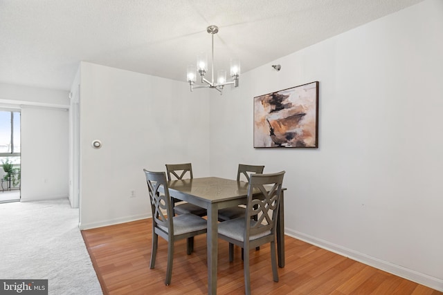 dining area featuring light wood-type flooring, baseboards, a chandelier, and a textured ceiling