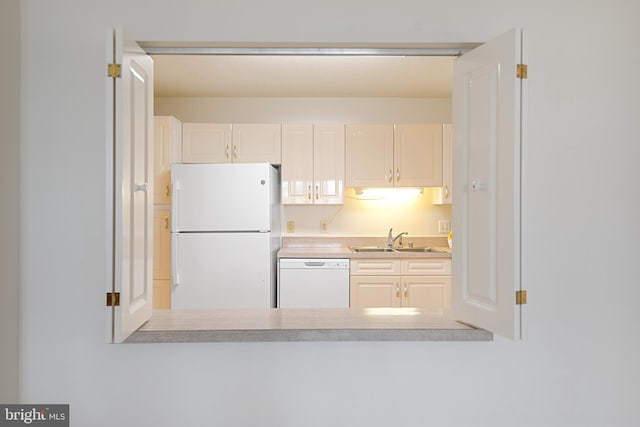 kitchen featuring white appliances, white cabinetry, light countertops, and a sink