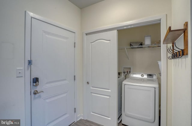 laundry room with washer / clothes dryer and light hardwood / wood-style flooring