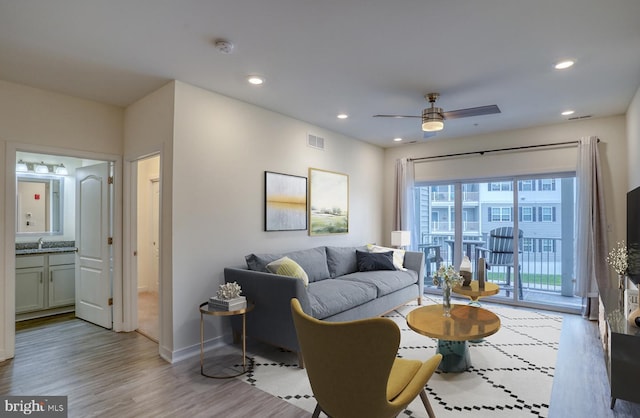 living room featuring ceiling fan, sink, and light hardwood / wood-style flooring