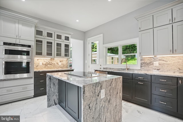 kitchen with a center island, black electric stovetop, sink, decorative backsplash, and stainless steel double oven