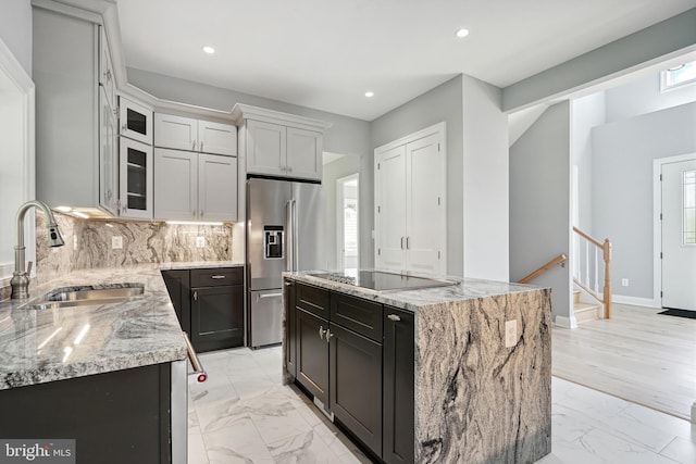 kitchen featuring black electric stovetop, a kitchen island, sink, and high end refrigerator