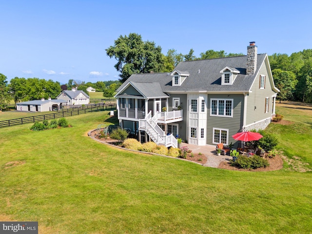 back of house with a wooden deck, a sunroom, a lawn, and a patio area