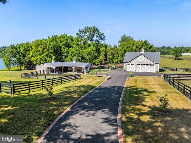 view of front of home featuring an outdoor structure, a front yard, and a rural view