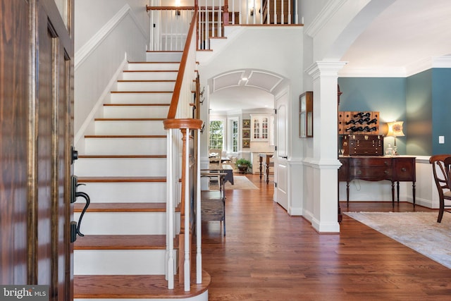 foyer entrance with ornamental molding, wood-type flooring, and ornate columns