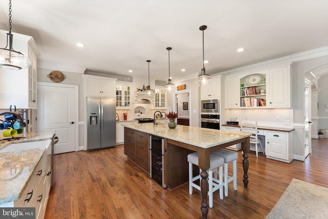 kitchen with stainless steel appliances, white cabinetry, hanging light fixtures, and a spacious island