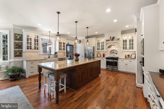 kitchen featuring an island with sink, appliances with stainless steel finishes, decorative backsplash, and decorative light fixtures