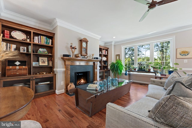 living room with crown molding, wood-type flooring, and ceiling fan