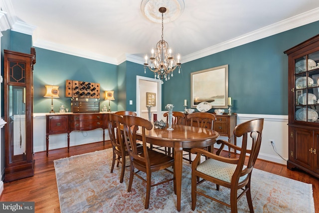 dining space with crown molding, dark hardwood / wood-style floors, and an inviting chandelier