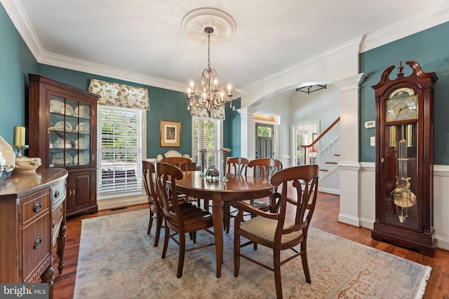 dining area featuring crown molding, dark wood-type flooring, and decorative columns