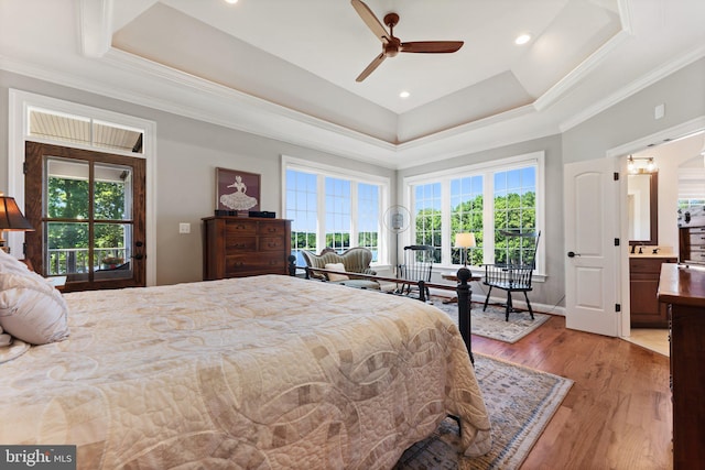 bedroom featuring multiple windows, a tray ceiling, ceiling fan, and light wood-type flooring