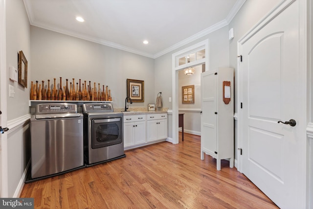 laundry area with sink, cabinets, light wood-type flooring, ornamental molding, and independent washer and dryer