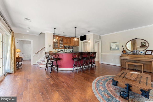 interior space with crown molding, fridge, stainless steel microwave, a kitchen breakfast bar, and dark hardwood / wood-style flooring