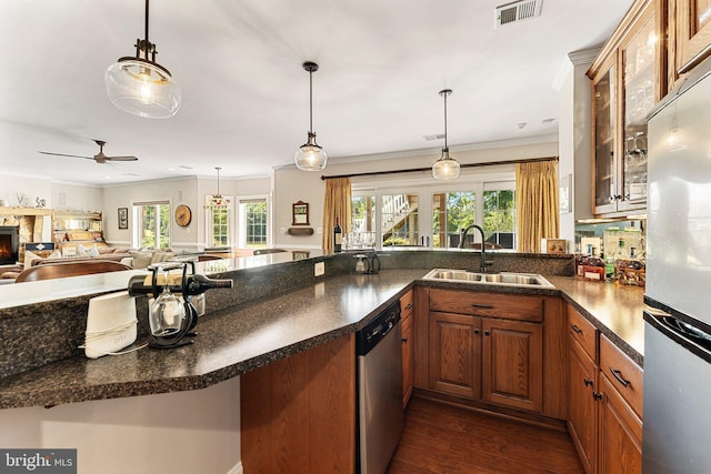 kitchen featuring a stone fireplace, pendant lighting, sink, kitchen peninsula, and stainless steel appliances