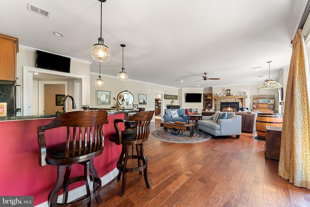 bar featuring hanging light fixtures, wood-type flooring, ceiling fan, and crown molding